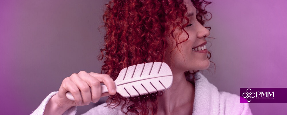 A person with red curly hair holding a white hair brushAI-generated content may be incorrect.